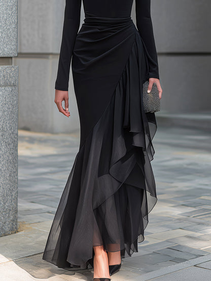 Vestido largo tipo sirena negro, con hombros descubiertos, cuello vuelto, mangas largas, volantes de gasa y corte drapeado